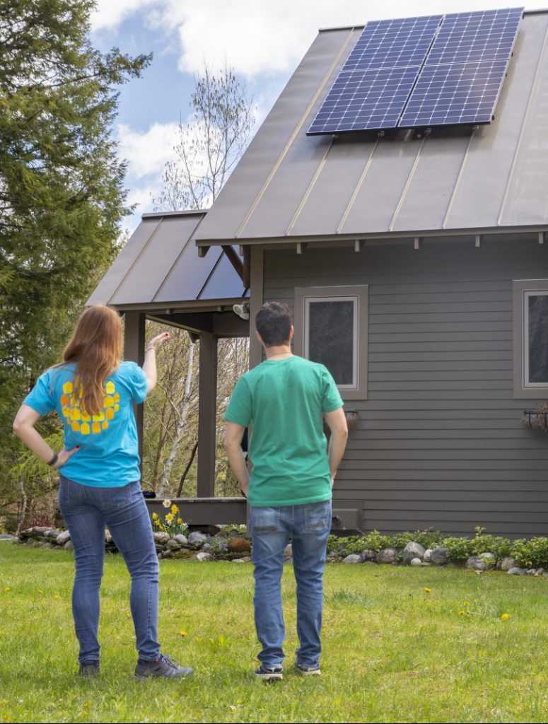 customer experience manager marlaina pointing at suncommon solar installation on roof