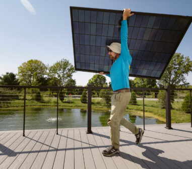 SunCommon solar installer carrying a rooftop solar panel in Vermont
